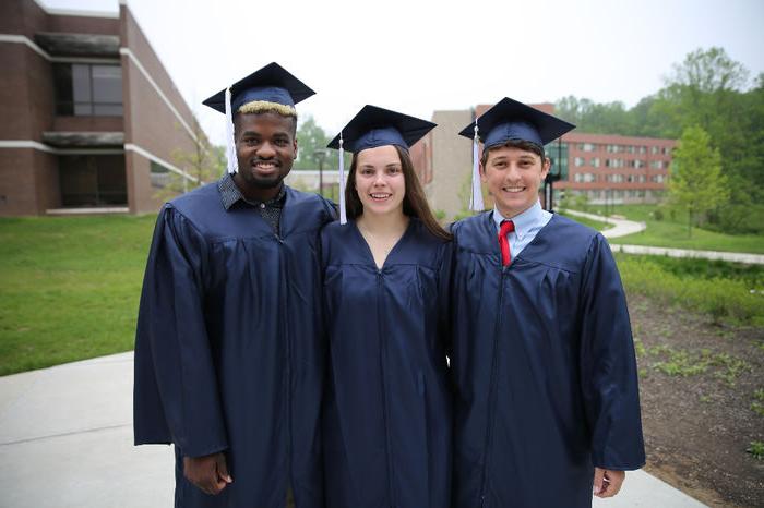 Three students smiling after Commencement ceremony.