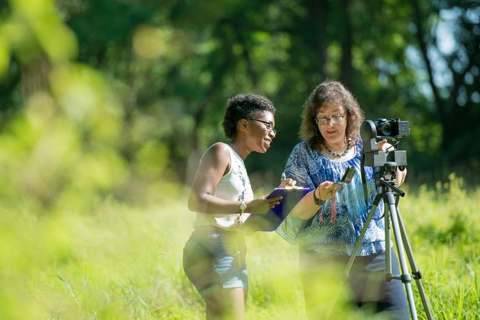 Professor and student conducting research outside.