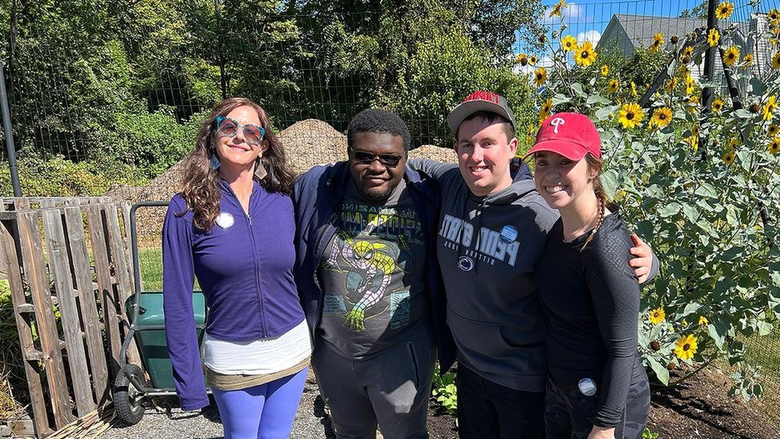 Students and garden manager standing in front of sun flowers