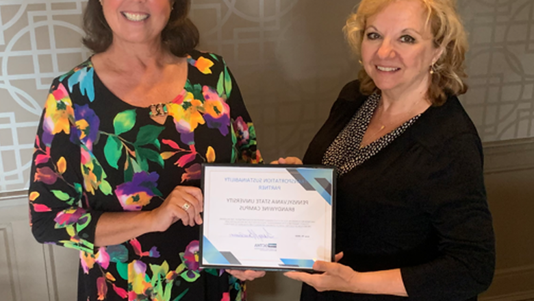 Two women hold up certificate at ceremony