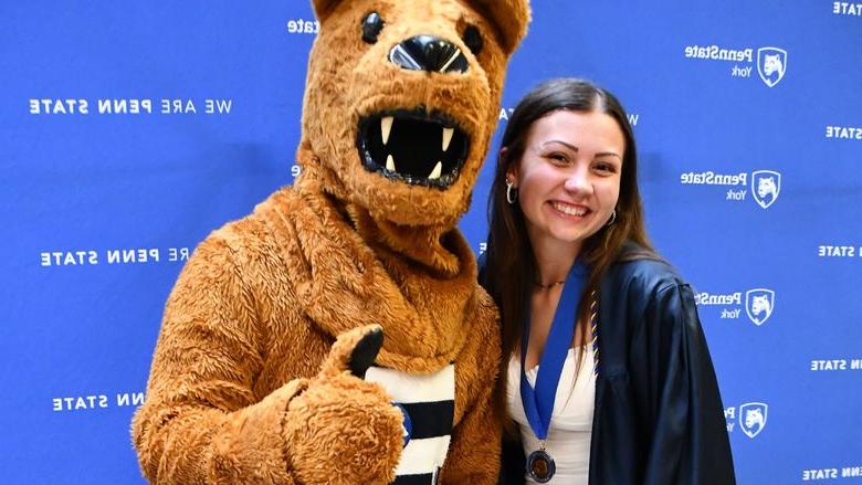 Female student standing next to the Nittany Lion mascot.